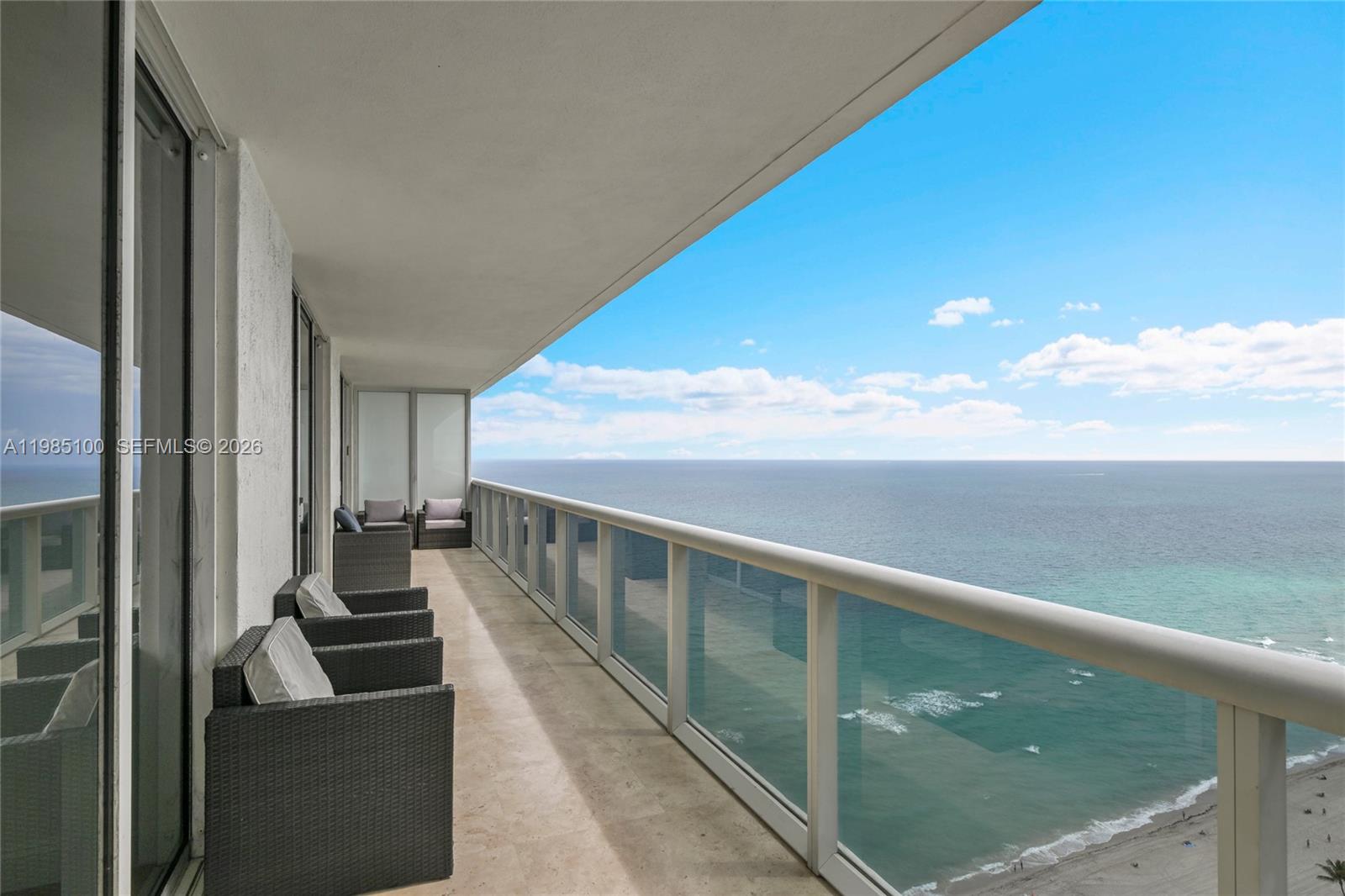 A balcony with wicker chairs overlooks the ocean and a sandy beach — 1830 S Ocean Dr # 3104, Hallandale Beach FL 33009, HALLANDALE BEACH, FL