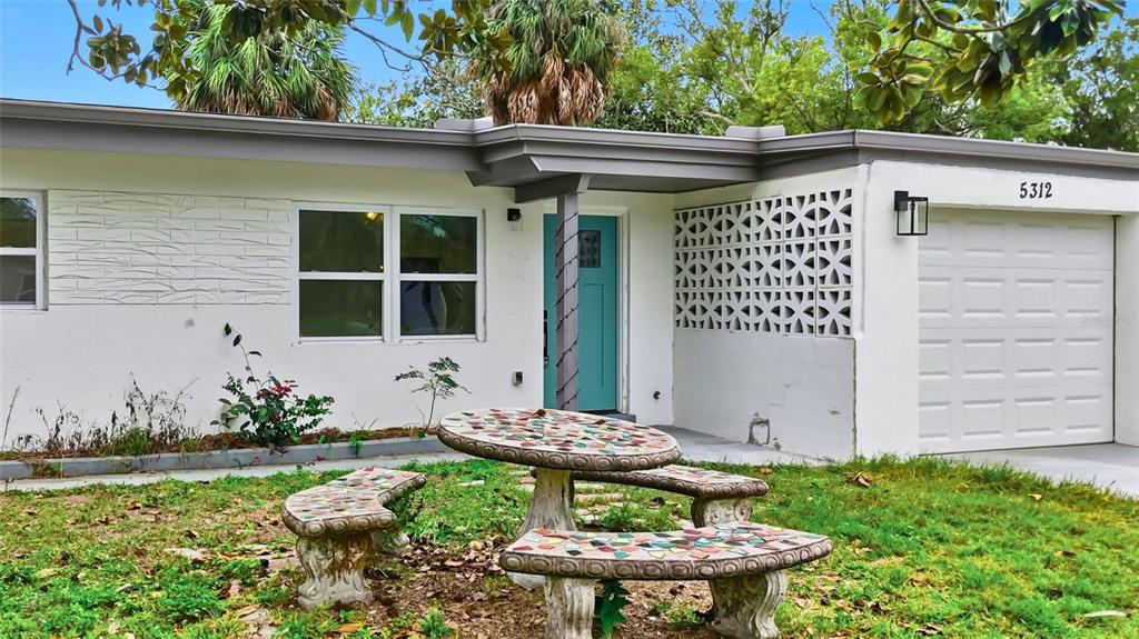 A single-story house features a teal front door, decorative breeze blocks, and a mosaic table — 5312 BERKLEY ROAD, NEW PORT RICHEY, FL