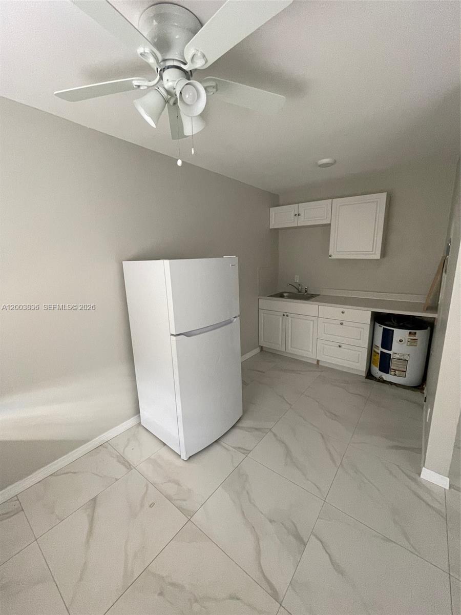 A small kitchen features white cabinets, a refrigerator, a sink, and a water heater — 1101 S K St # 16, Lake Worth FL 33460, LAKE WORTH, FL