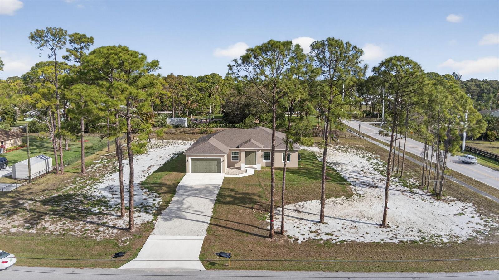 An aerial view shows a single-story house with a garage surrounded by pine trees — 14043 87th Street N, Loxahatchee FL 33470, LOXAHATCHEE, FL