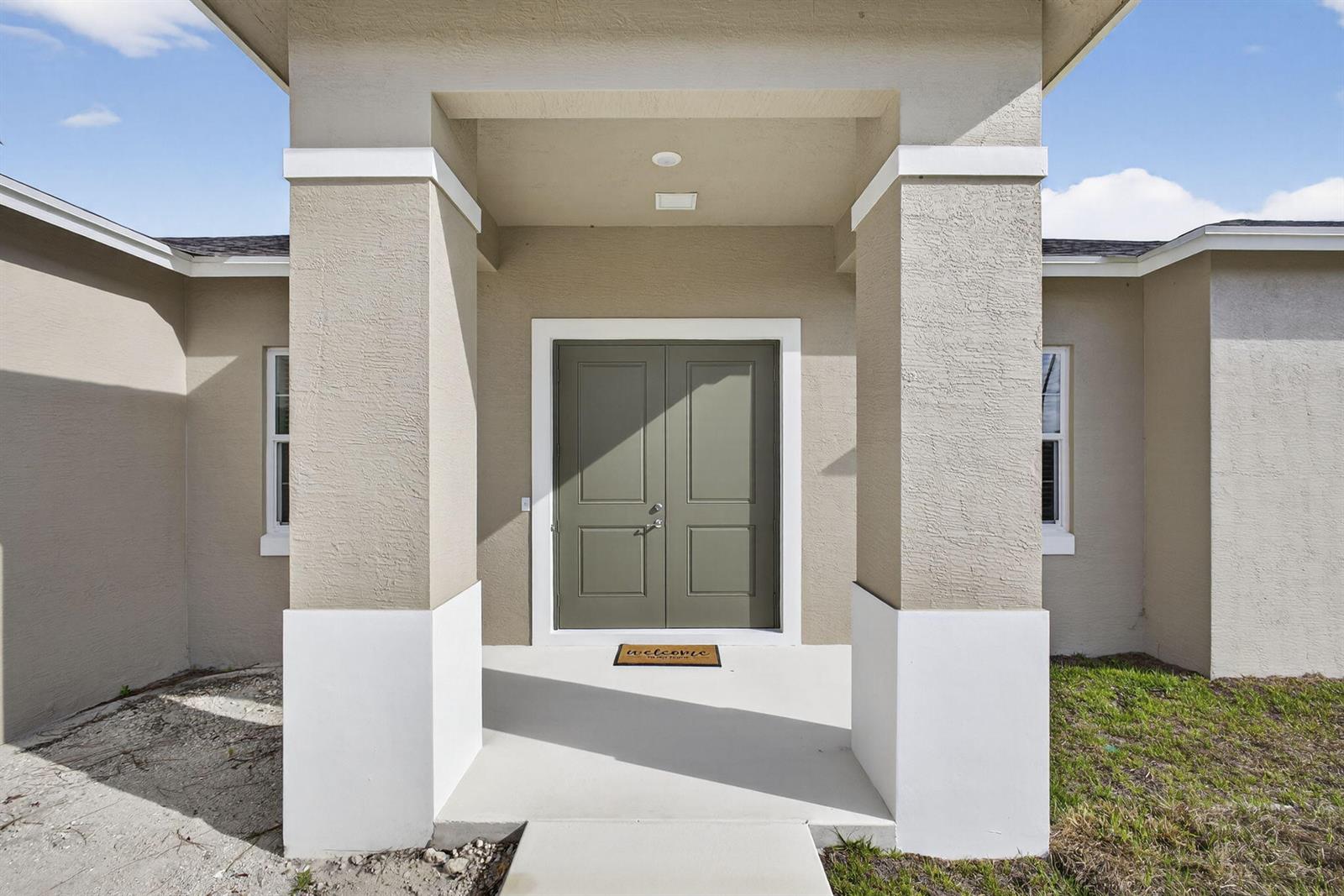 The exterior view shows a tan house with a covered entryway and double green doors — 14043 87th Street N, Loxahatchee FL 33470, LOXAHATCHEE, FL