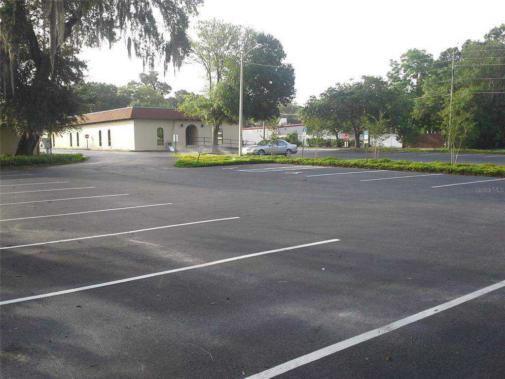 An asphalt parking lot sits in front of a tan building with a brown roof — 1302 N MAIN STREET, KISSIMMEE, FL