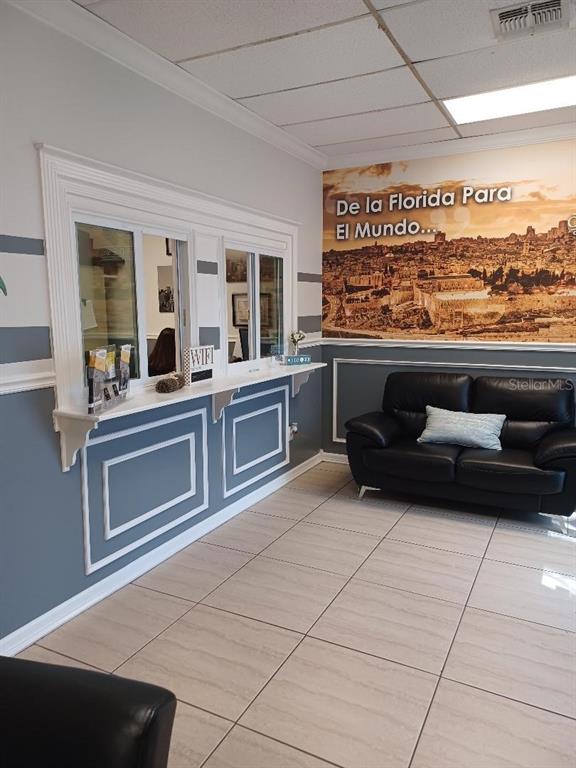 An office waiting area features a service window, a black leather sofa, and wall mural — 1302 N MAIN STREET, KISSIMMEE, FL