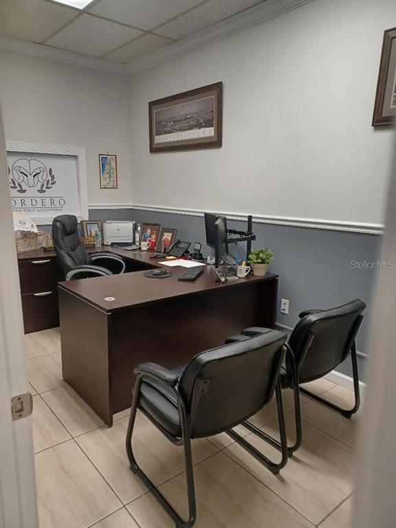 A professional office features a dark wood desk, black chairs, and a logo on the wall — 1302 N MAIN STREET, KISSIMMEE, FL