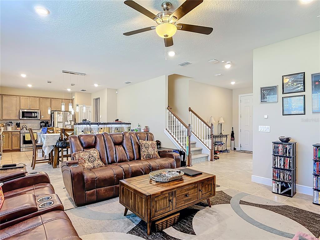A living room with a brown leather sofa, coffee table, and an open kitchen area — 2248 CANOPY TERRACE BOULEVARD, DELAND, FL