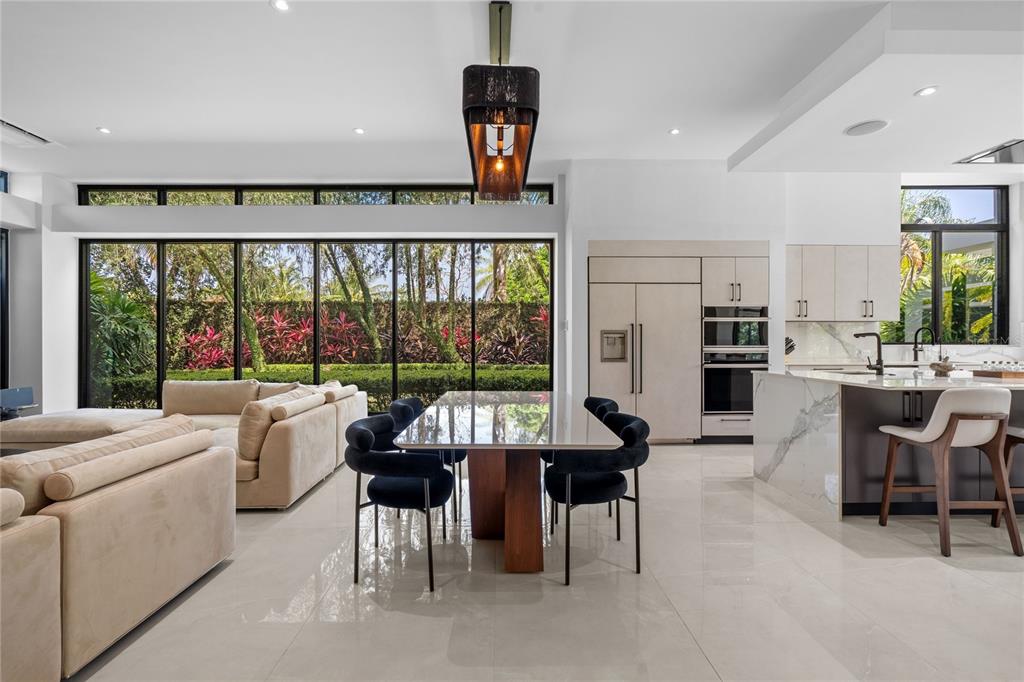 A modern open-concept living and dining area features floor-to-ceiling windows, tile flooring, and a kitchen — 366 DORADO BEACH EAST, DORADO, PR