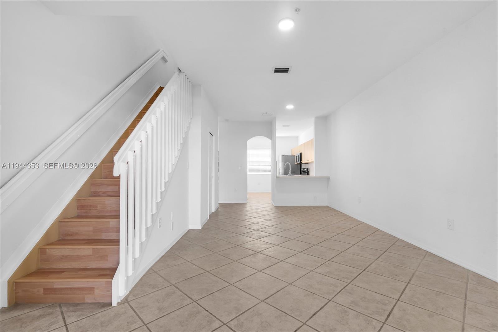 An interior view shows a tiled living area with a staircase and an open kitchen — 5670 NW 116th Ave # 219, Doral FL 33178, DORAL, FL