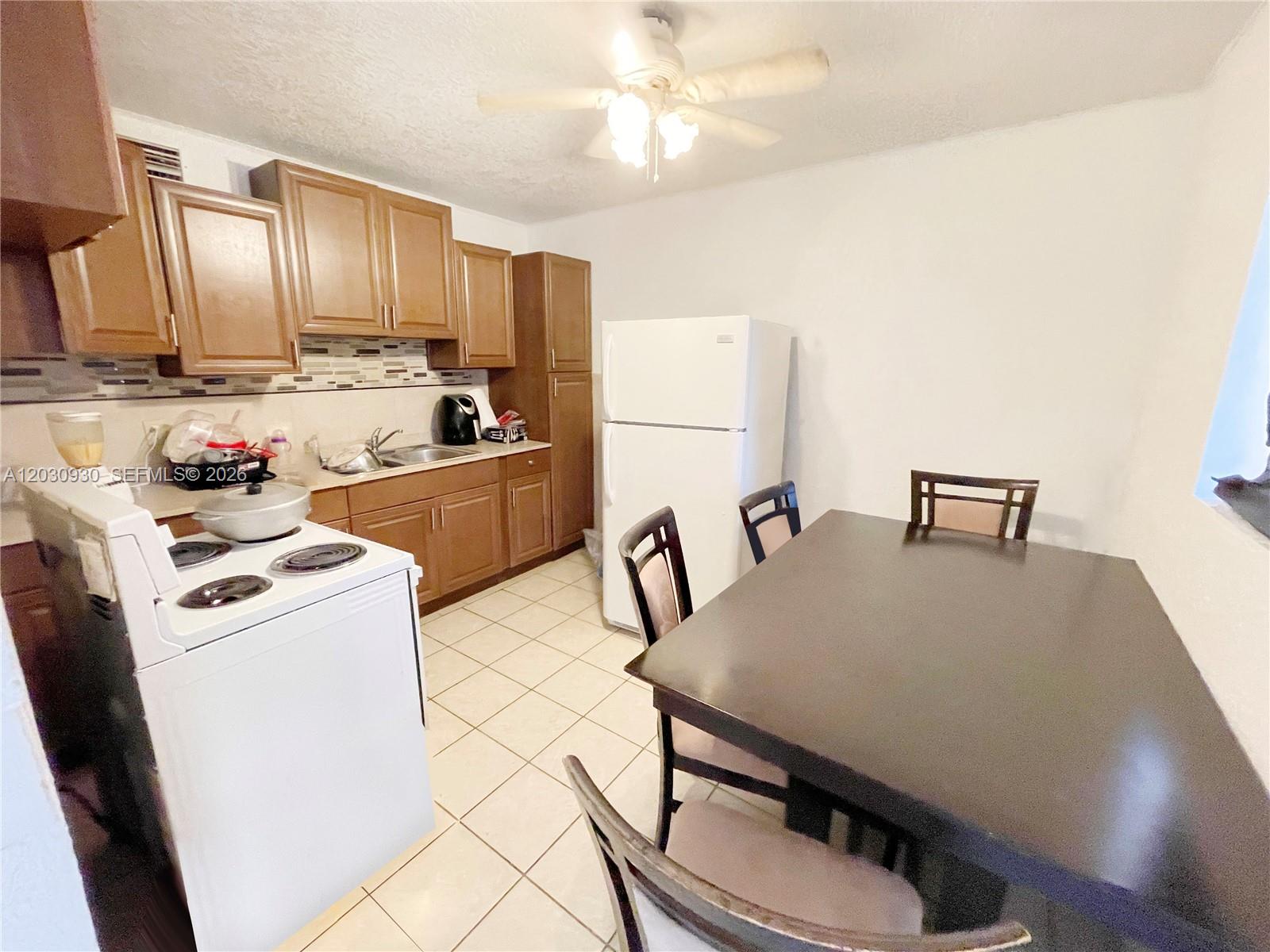 A kitchen features brown cabinets, white appliances, tile flooring, and a dining table — 1829 N A St # 51, Lake Worth FL 33460, LAKE WORTH, FL