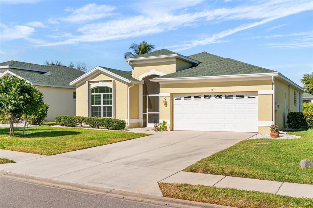 A single-story yellow house with a green roof and a two-car garage — 1777 EMERALD COVE CIRCLE, CAPE CORAL, FL