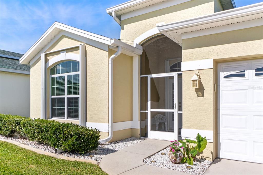 A tan house exterior features a white screen door, a garage, and a landscaped front yard — 1777 EMERALD COVE CIRCLE, CAPE CORAL, FL