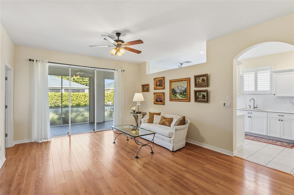 A living room with hardwood floors, a glass coffee table, and a view of a patio — 1777 EMERALD COVE CIRCLE, CAPE CORAL, FL