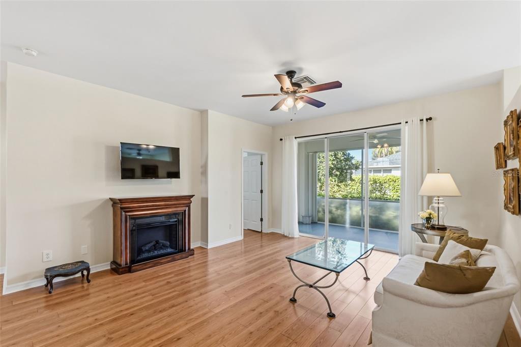 A living room features a fireplace, wall-mounted television, ceiling fan, and sliding glass patio doors — 1777 EMERALD COVE CIRCLE, CAPE CORAL, FL
