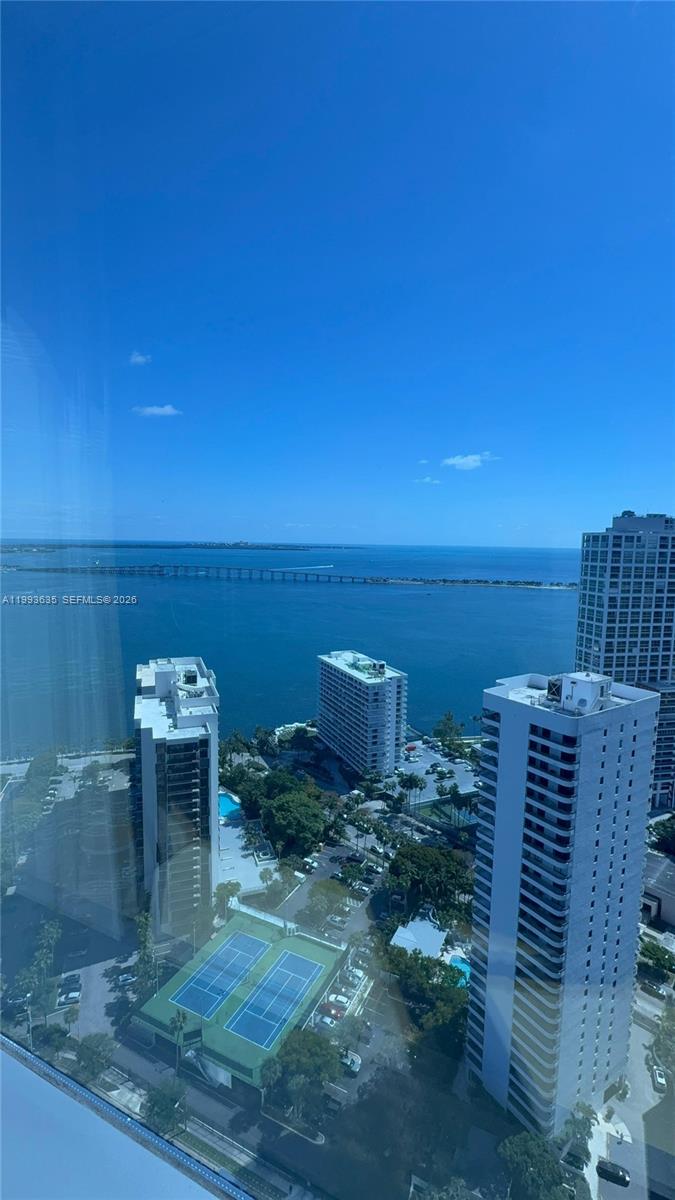 A high-angle view shows a coastal city skyline with tall buildings, tennis courts, and water — 1435 Brickell Ave # 3305, Miami FL 33131, MIAMI, FL