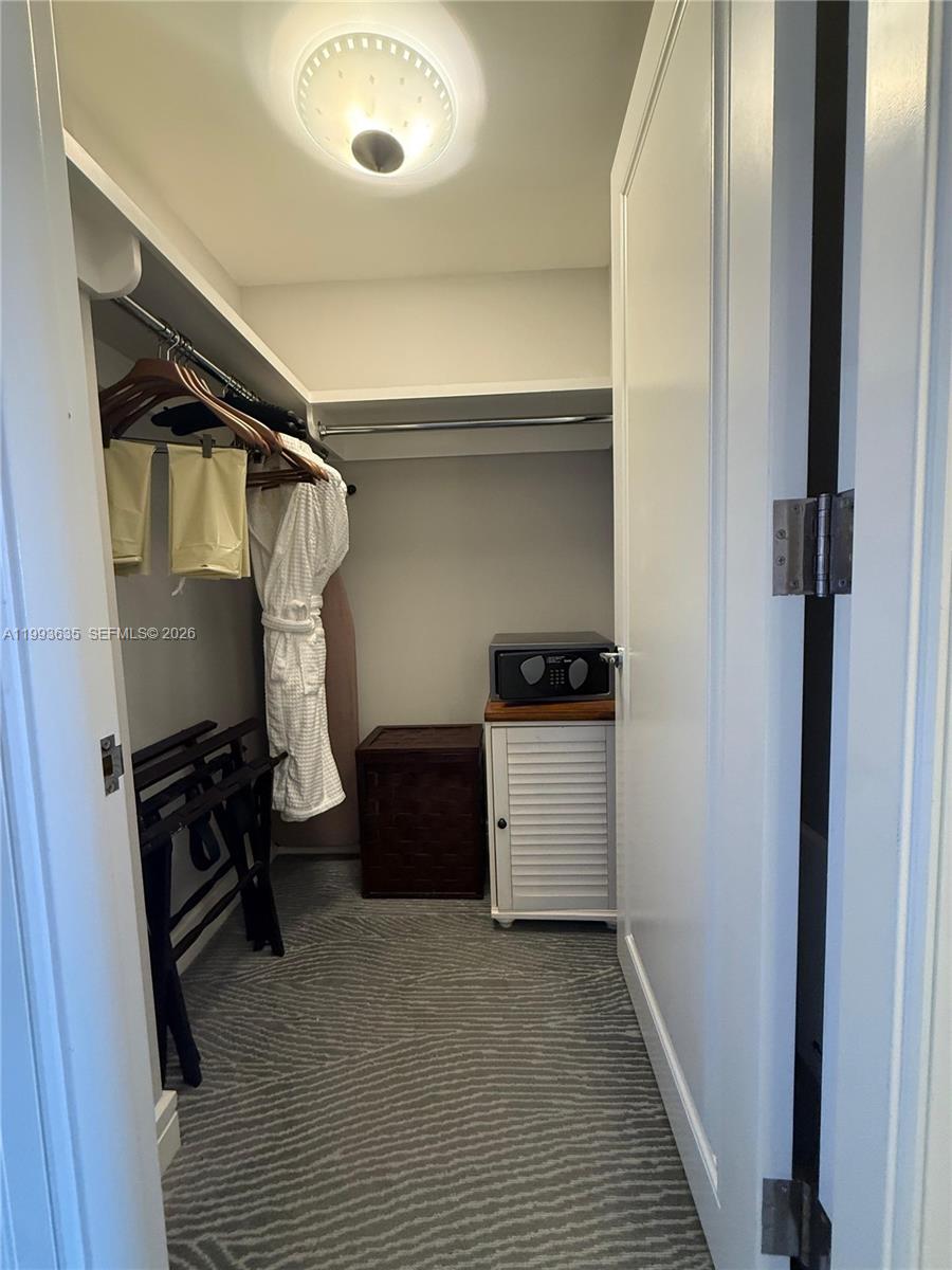 A walk-in closet features a hanging rod, a safe, storage furniture, and patterned carpeting — 1435 Brickell Ave # 3305, Miami FL 33131, MIAMI, FL