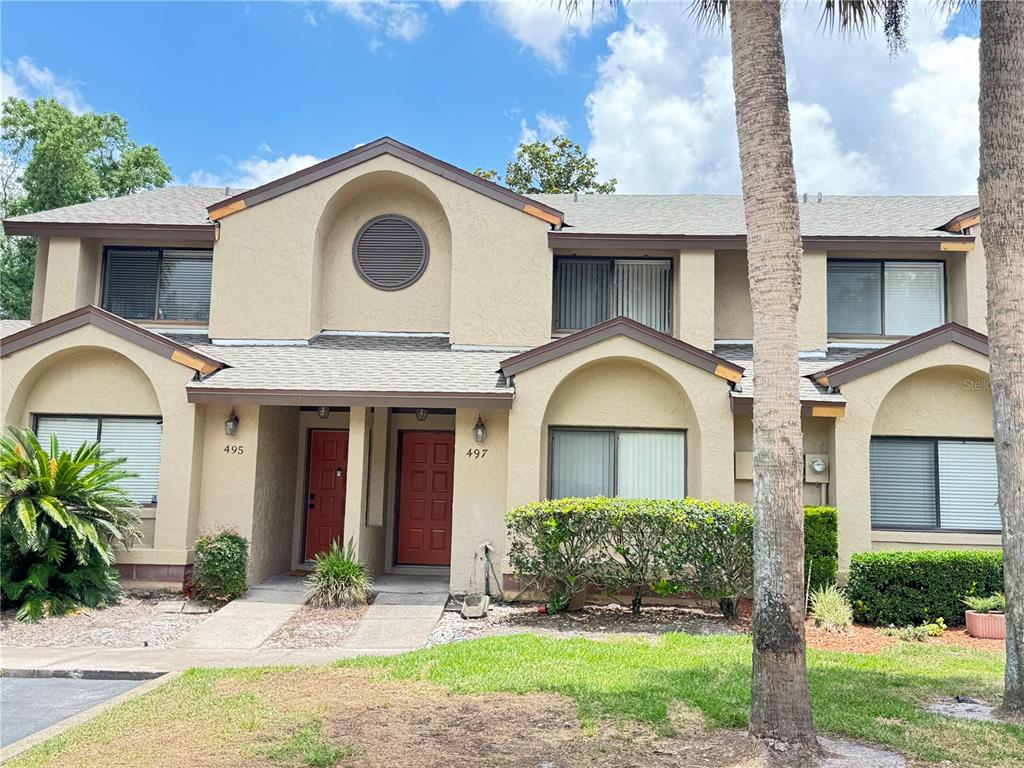 A high-ceilinged room features tiled flooring, a fireplace, a ceiling fan, and sliding glass doors — 497 CLUB DRIVE, WINTER SPRINGS, FL