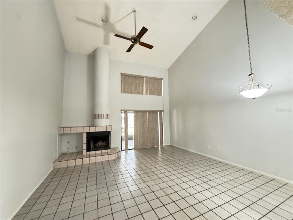 A living room with a tiled floor, a fireplace, a ceiling fan, and a sliding door — 497 CLUB DRIVE, WINTER SPRINGS, FL