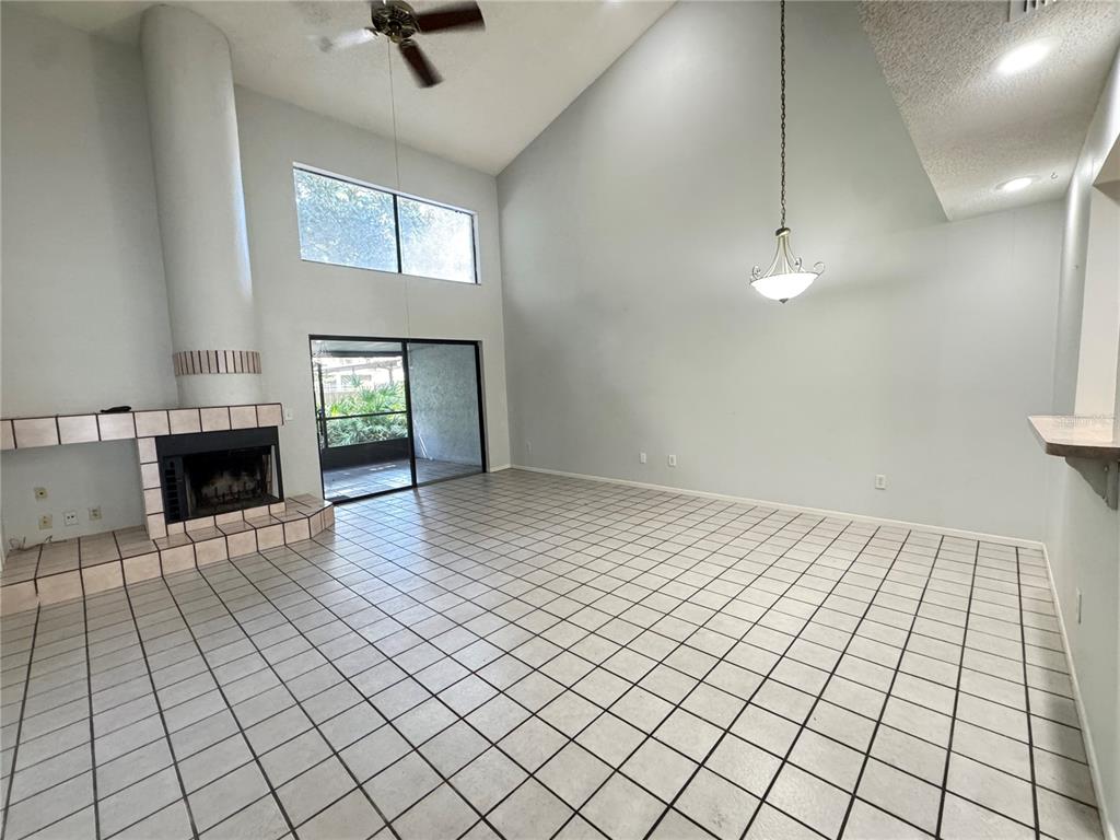 An empty living room with tiled floors, a high ceiling, and an open loft balcony — 497 CLUB DRIVE, WINTER SPRINGS, FL