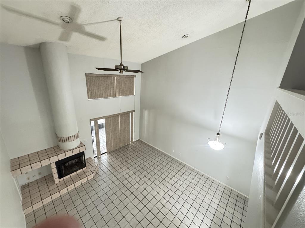 A high-ceilinged living room features a tiled fireplace, a ceiling fan, and tiled flooring — 497 CLUB DRIVE, WINTER SPRINGS, FL