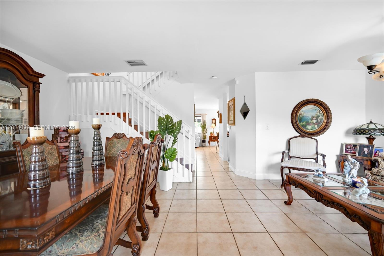 A dining room and living area feature tile floors, a wooden staircase, and traditional furniture — 9732 SW 166th Ct, Miami FL 33196, MIAMI, FL