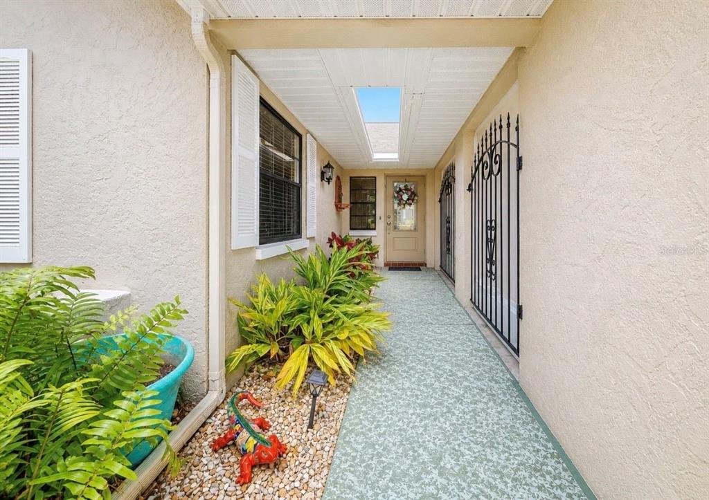 A covered outdoor walkway leads to a front door with a skylight above — 319 LINGER LANE, SUN CITY CENTER, FL
