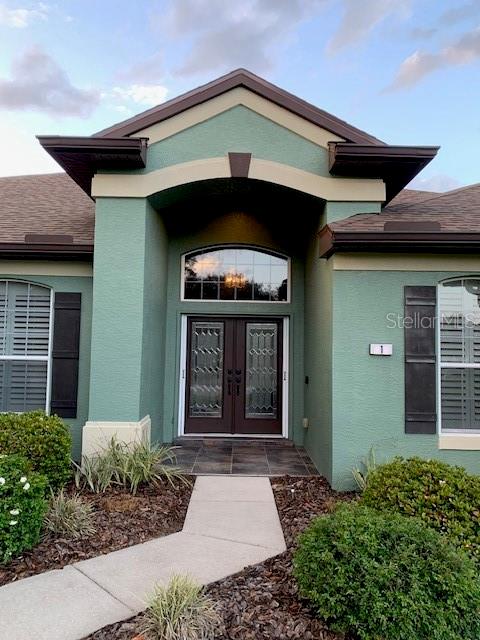 The exterior of a green house features a covered entryway with double glass-paneled front doors — 1 MINTWOOD POINT, HOMOSASSA, FL