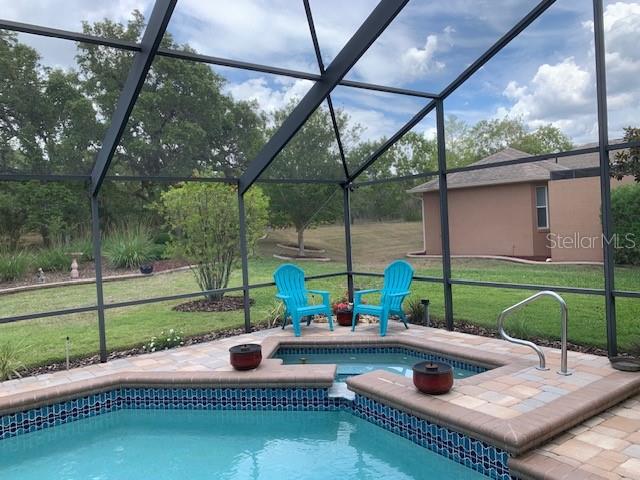 A screened-in pool area features a spa, two blue chairs, and a view of the backyard — 1 MINTWOOD POINT, HOMOSASSA, FL