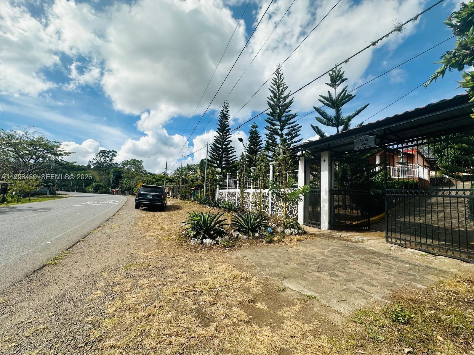 A gated entrance with a stone driveway sits beside a road and tall pine trees — Quinta Los Cedros Matagalpa, Nicaragua, FL, FL