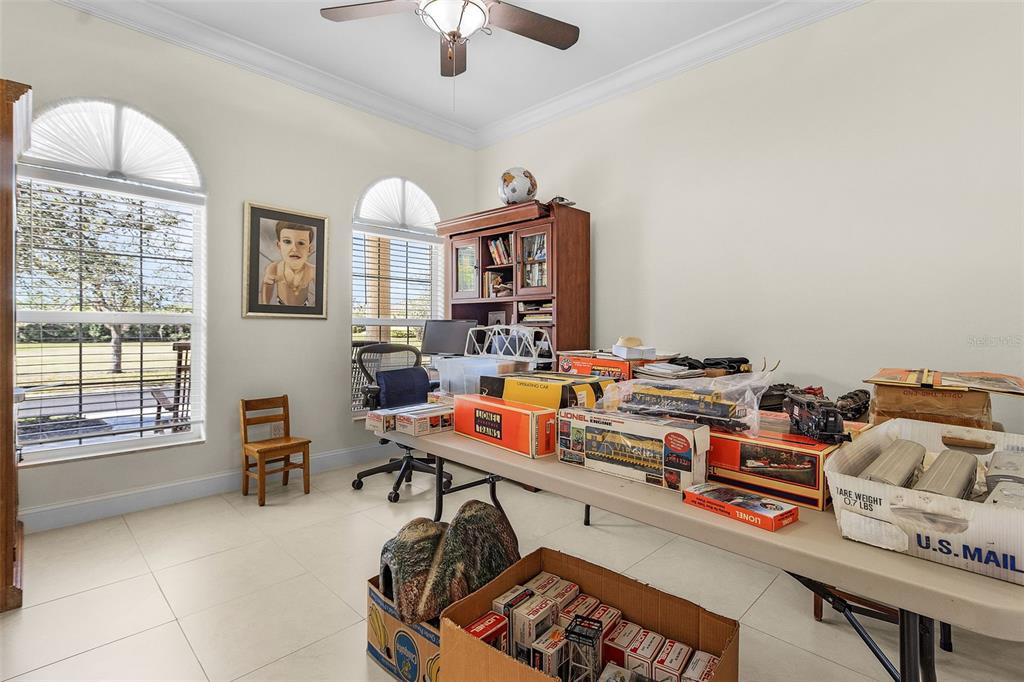 A room with tile floors, two arched windows, and a table covered in model train boxes — 21370 HARBORSIDE BOULEVARD, PORT CHARLOTTE, FL