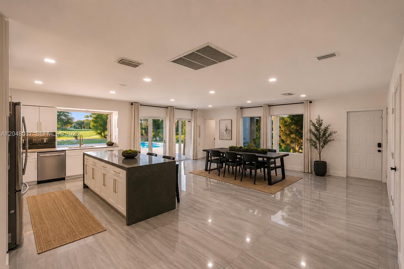 A modern kitchen and dining area feature a large island, tile floors, and pool views — 4740 N 31st Ct, Hollywood FL 33021, HOLLYWOOD, FL