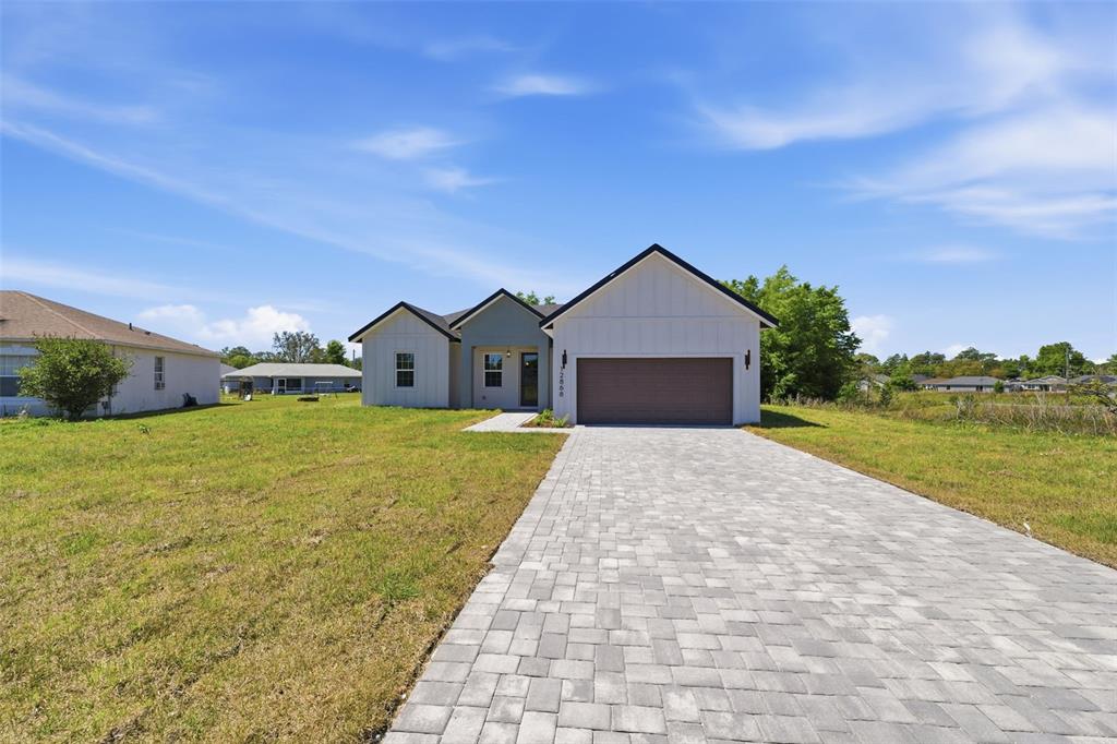 A modern single-story house with a white exterior, dark roof, and a paved driveway — 12868 SW 73RD TERRACE, OCALA, FL