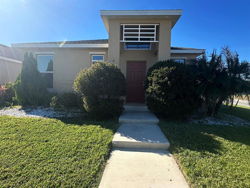 A single-story house with a tan exterior, a red front door, and two large bushes — 3100 ROCKY RIVER ROAD, KISSIMMEE, FL
