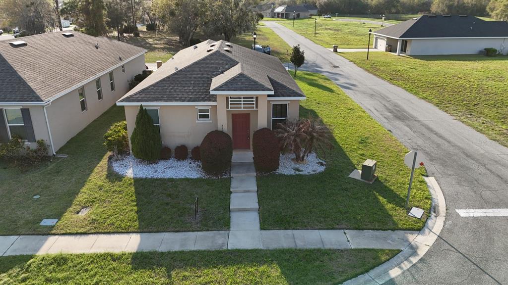 An aerial view shows the front exterior of a single-story house with a red door — 3100 ROCKY RIVER ROAD, KISSIMMEE, FL