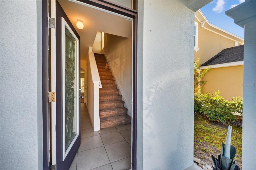 An open front door reveals a tiled entryway with a carpeted staircase leading upstairs — 4842 SAN PALERMO DRIVE, BRADENTON, FL