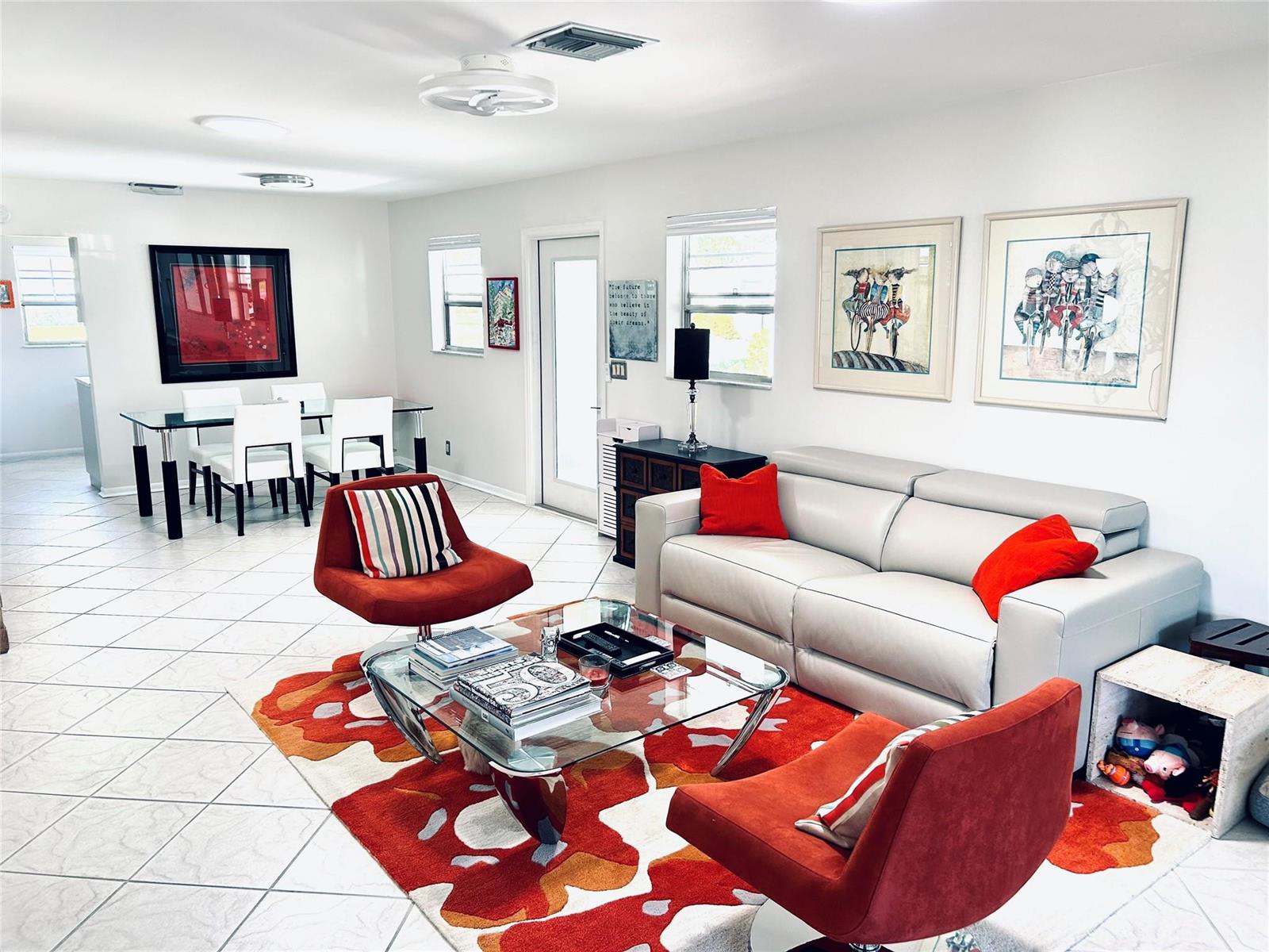 A living and dining area features white tile floors, a glass coffee table, and orange accents — 850 Meadowlark Lane, Delray Beach FL 33445, DELRAY BEACH, FL