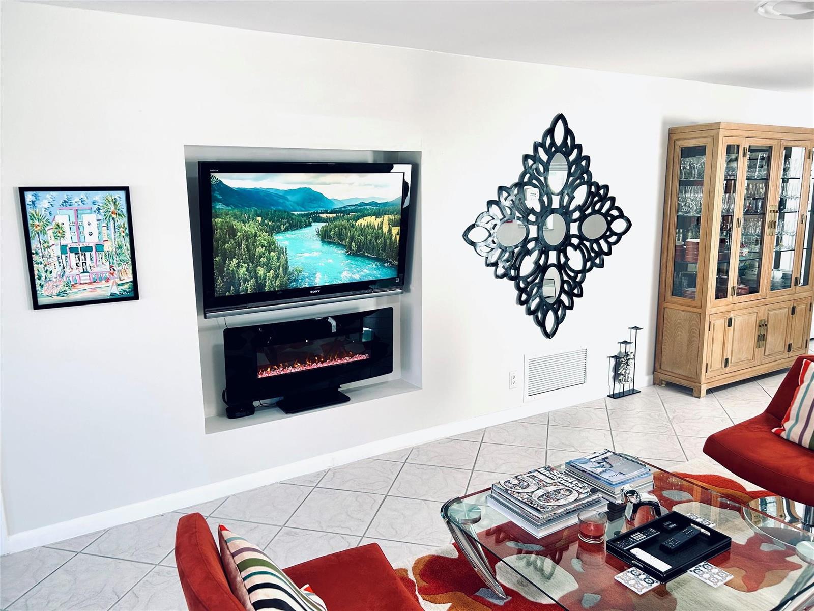 A living room features a recessed television and fireplace, a decorative wall mirror, and furniture — 850 Meadowlark Lane, Delray Beach FL 33445, DELRAY BEACH, FL
