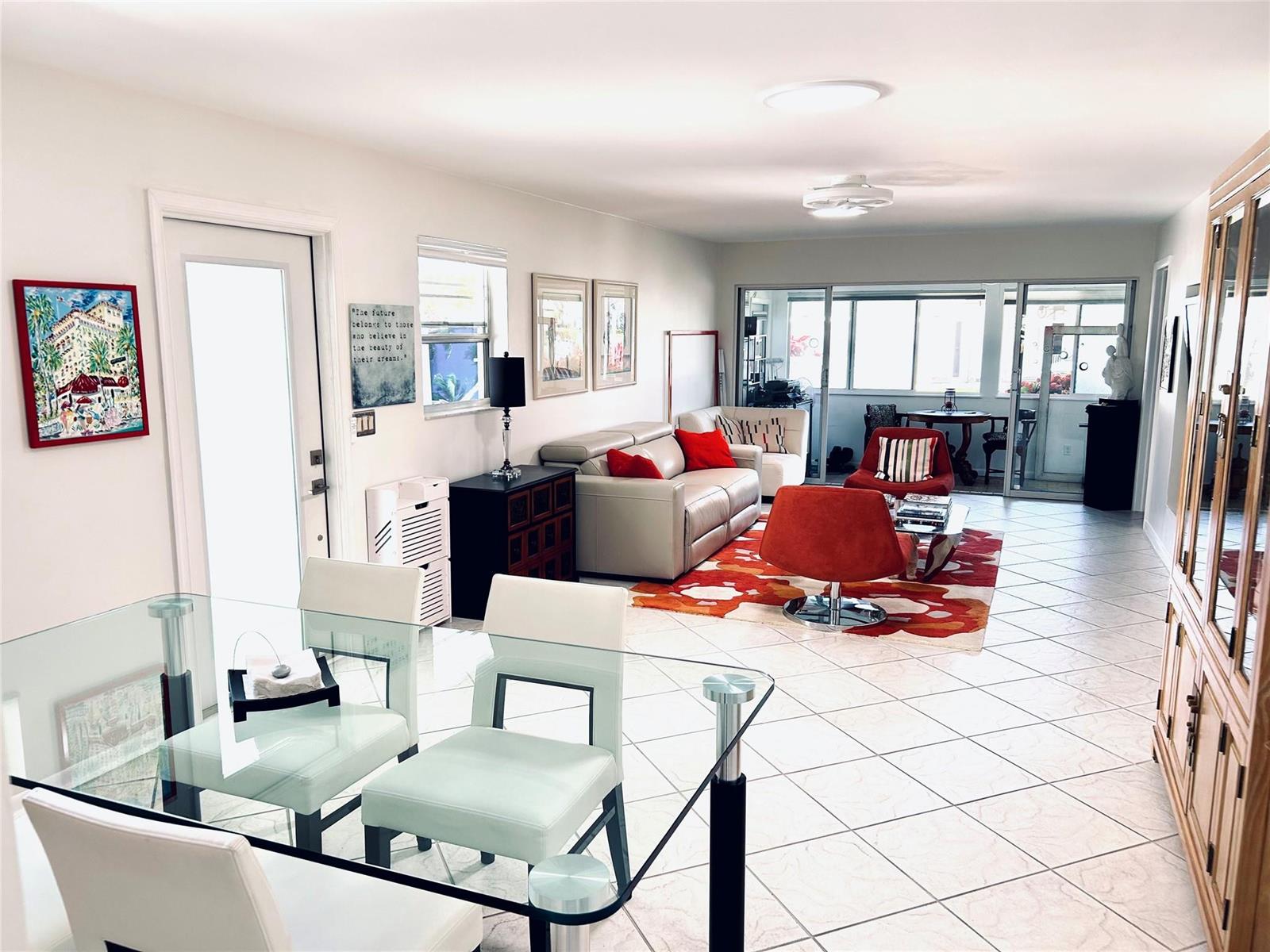 A bright living and dining area with tile floors, a glass table, and red accents — 850 Meadowlark Lane, Delray Beach FL 33445, DELRAY BEACH, FL