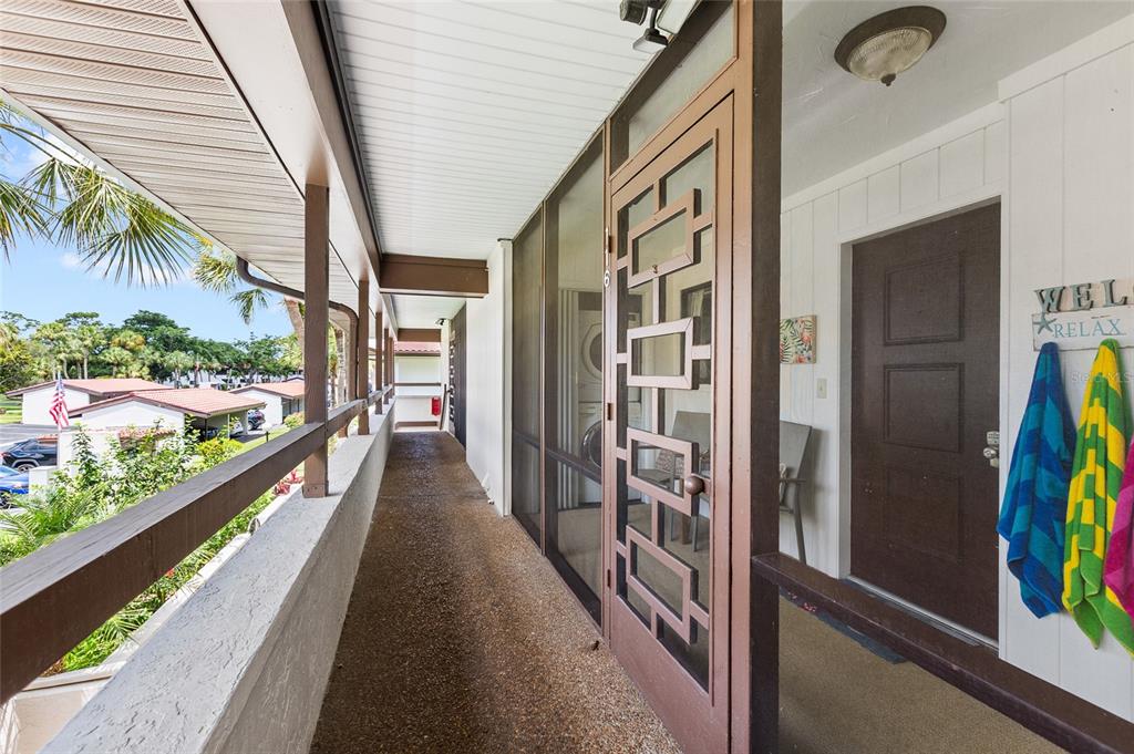 An outdoor walkway leads to a brown front door with a decorative metal screen door — 3500 EL CONQUISTADOR PARKWAY UNIT 116, BRADENTON, FL