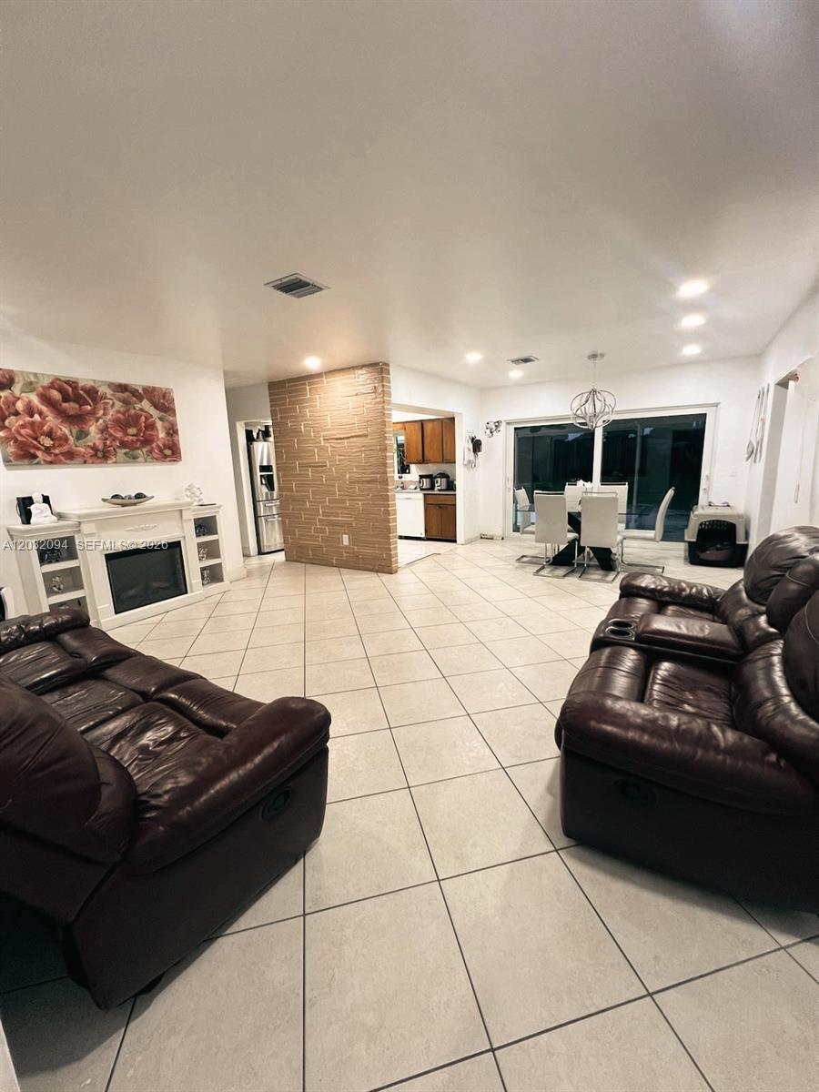 A living room features tile floors, a brick accent wall, and a white fireplace — 6492 SW 25th St, Miramar FL 33023, MIRAMAR, FL