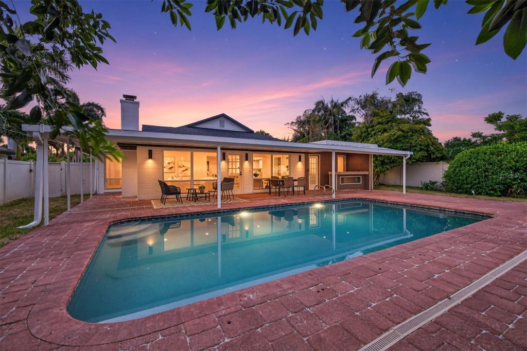 A backyard swimming pool with a brick patio sits in front of a single-story house — 219 MIRAMAR BOULEVARD NE, ST PETERSBURG, FL
