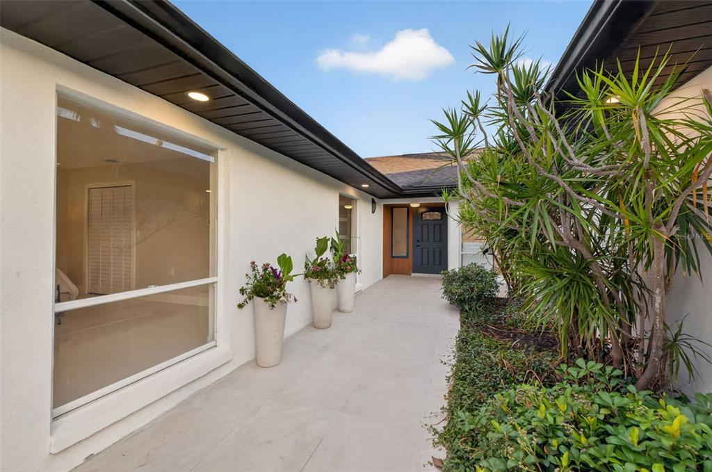 A paved walkway leads to a dark front door beside a large window and planters — 219 MIRAMAR BOULEVARD NE, ST PETERSBURG, FL