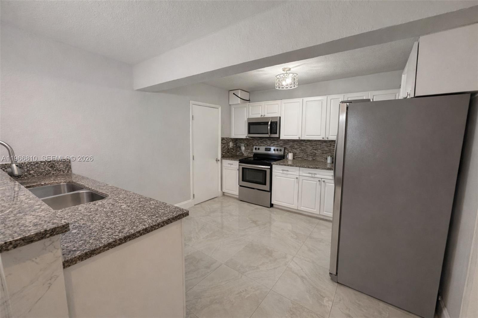 A kitchen features white cabinets, granite countertops, stainless steel appliances, and light-colored tile flooring — 4500 NW 3rd Ave, Miami FL 33127, MIAMI, FL
