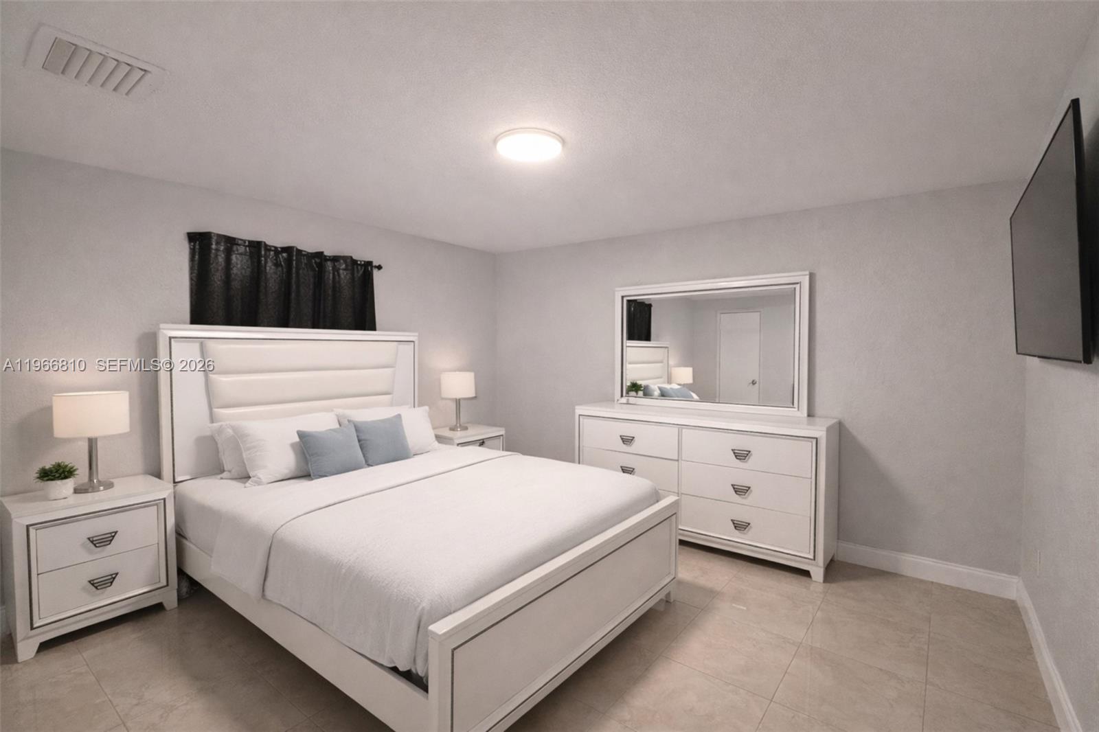 A bedroom features a white bed, matching dresser with mirror, and light-colored tile flooring — 4500 NW 3rd Ave, Miami FL 33127, MIAMI, FL