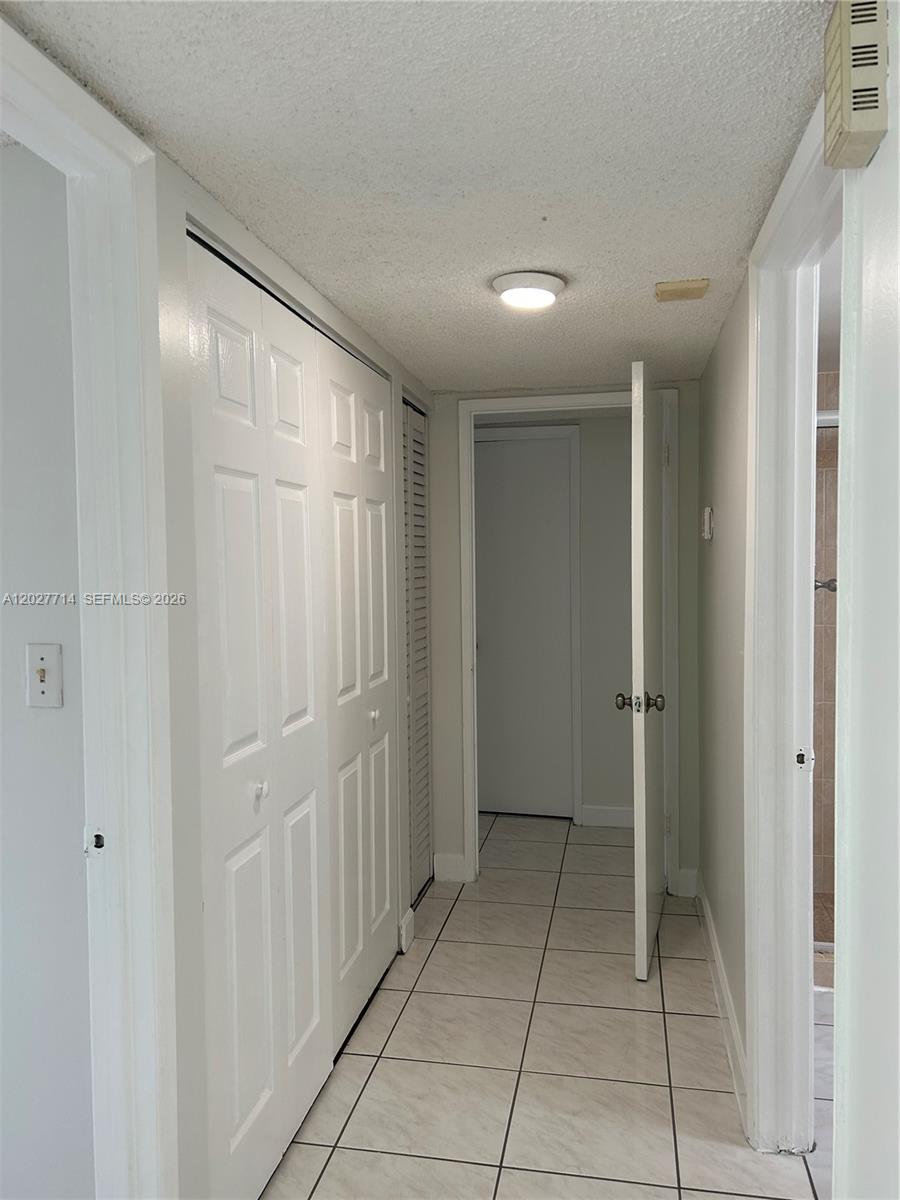 A hallway features white tile flooring, a closet with bifold doors, and two open doorways — MIAMI, FL