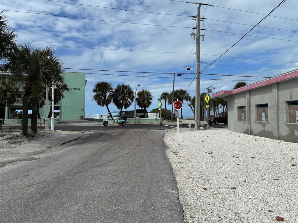 A paved road leads toward a stop sign near a beachside building and palm trees — 104 1ST STREET N, BRADENTON BEACH, FL