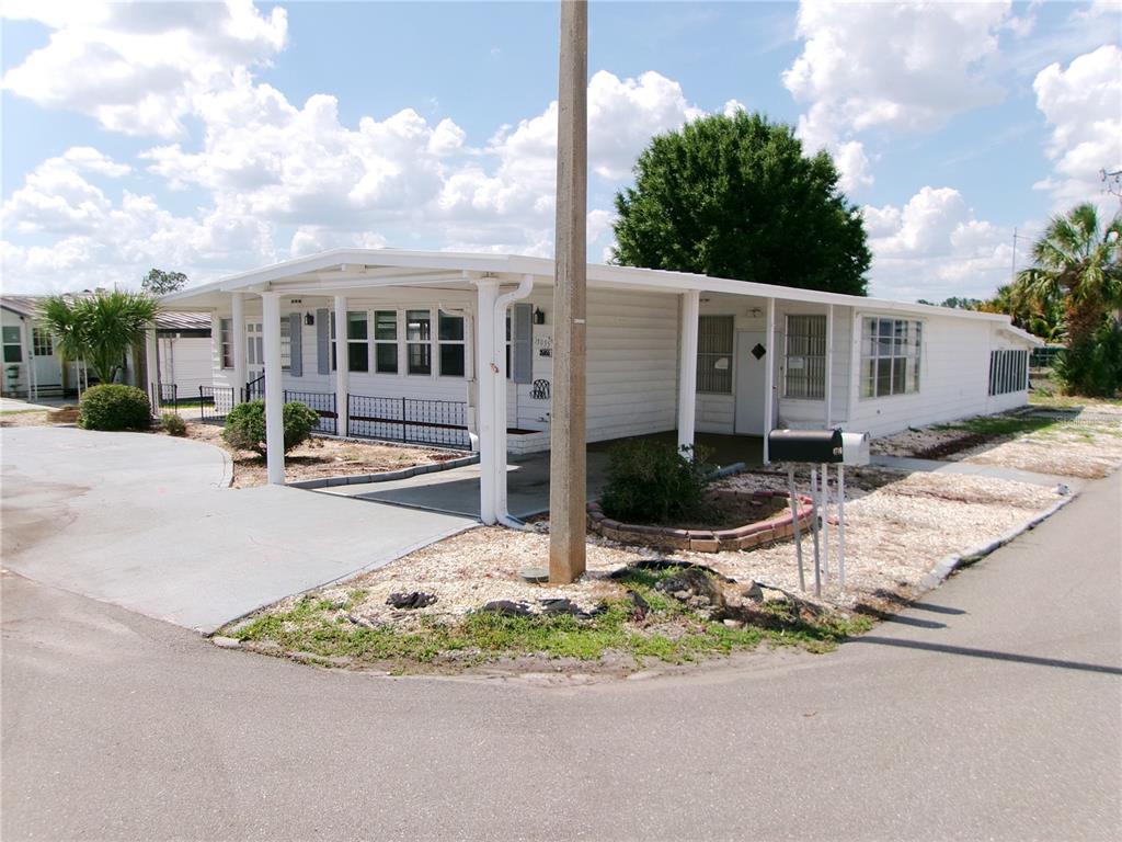 A white mobile home with a carport and a gravel front yard under a blue sky — 35055 DALE AVENUE, ZEPHYRHILLS, FL