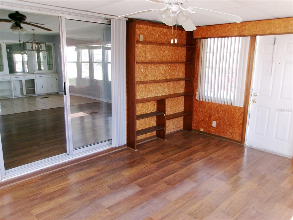 A room with wood-look flooring, a built-in bookshelf, sliding glass doors, and a ceiling fan — 35055 DALE AVENUE, ZEPHYRHILLS, FL