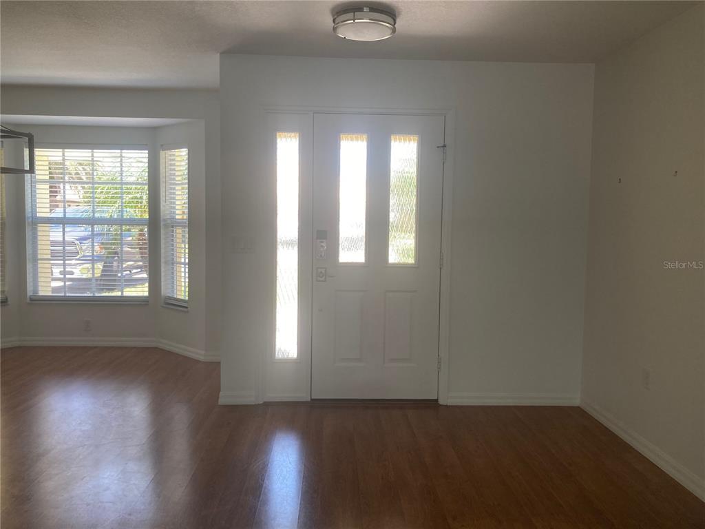 An entryway features a white front door with glass panels, light wood flooring, and windows — 4835 JACARANDA HEIGHTS DRIVE, VENICE, FL