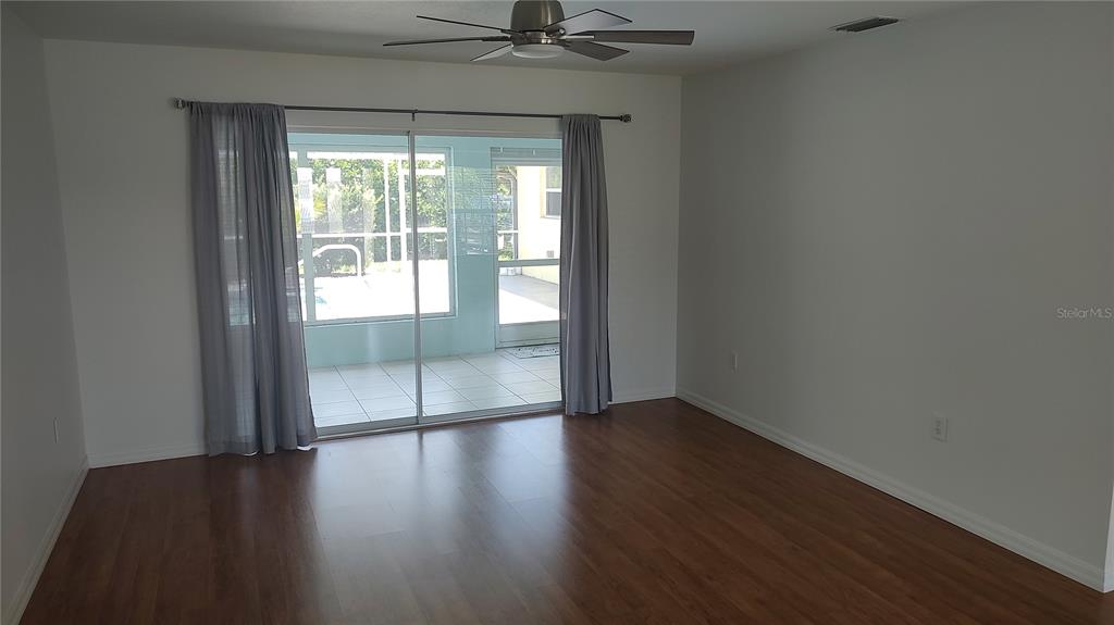 An empty room with wood-look flooring, a ceiling fan, and sliding glass doors to a lanai — 4835 JACARANDA HEIGHTS DRIVE, VENICE, FL