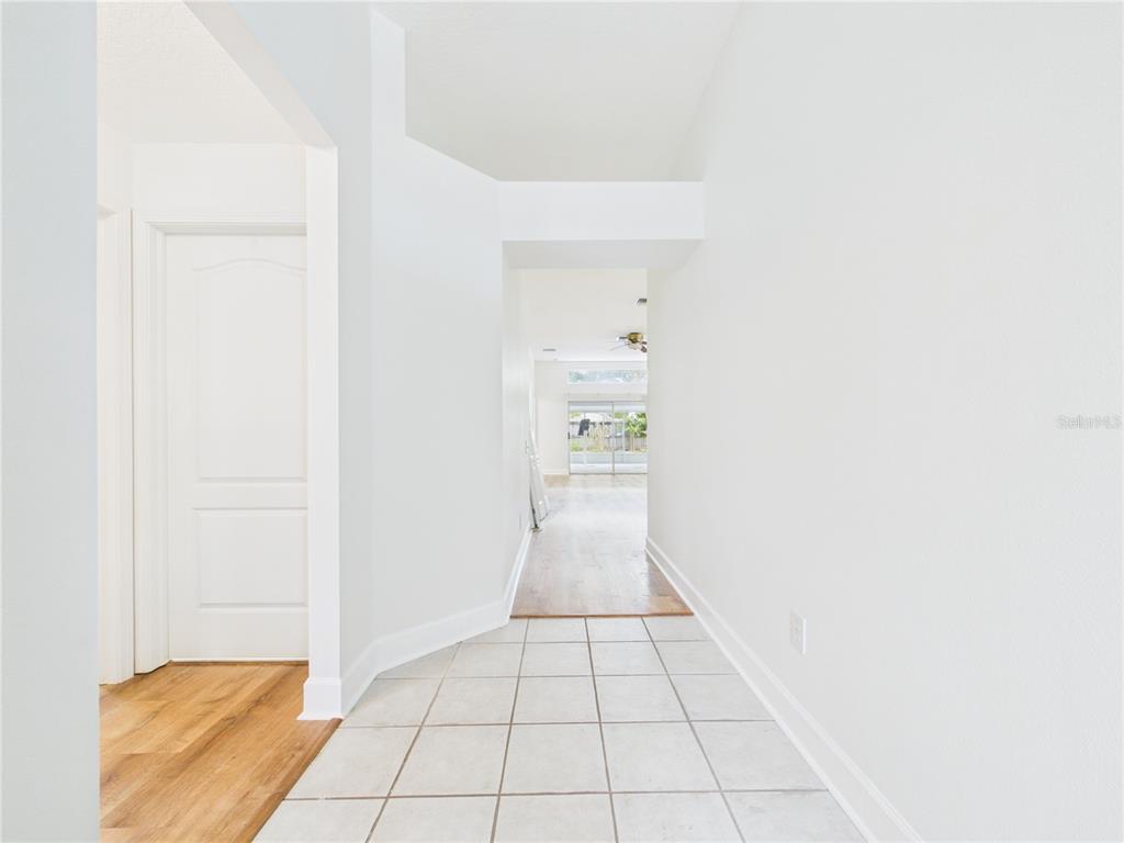 A tiled entryway leads into a hallway with wood flooring and a view of a patio — 10553 EGRET HAVEN LANE, RIVERVIEW, FL