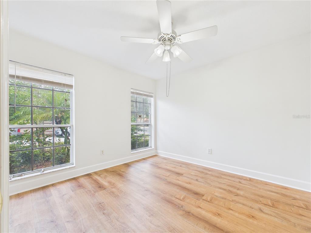 An empty bedroom features white walls, wood-look flooring, two windows, and a ceiling fan — 10553 EGRET HAVEN LANE, RIVERVIEW, FL